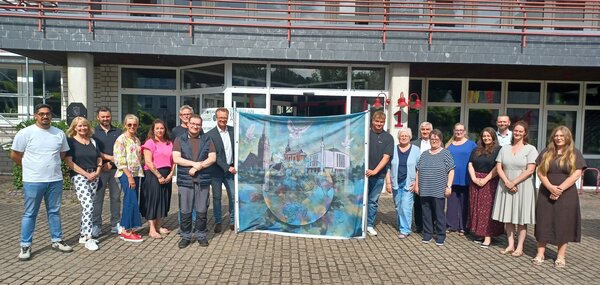 Bild vergr&ouml;&szlig;ern: Foto � Stadt Lennestadt. Die Mitglieder des Arbeitskreises Integration unter dem Vorsitz von Nedim Kalembasi (7.v.r.), B�rgermeister Tobias Puspas (8.v.l.) sowie Christa Maria J�rgens (musikalische Gesamtleitung (5.v.r.) freuen sich auf das interreligi�se Friedensgebet beim Stadtfestsonntag